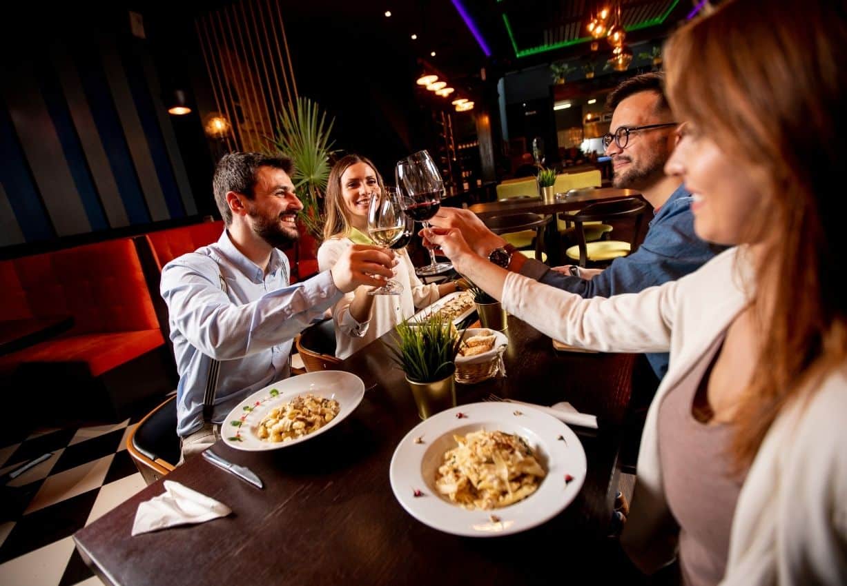 A Group Of People Clinking Glasses At A Restaurant